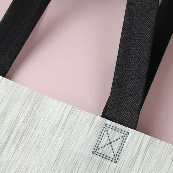 Stitched handle design on nonwoven packaging bag